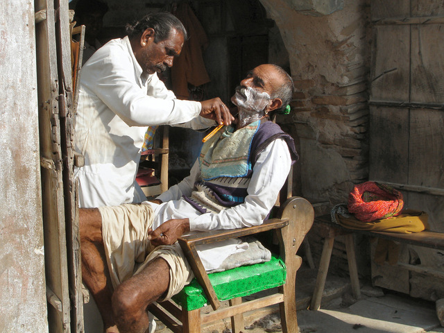 holič v Indickém městě se zákazníkem